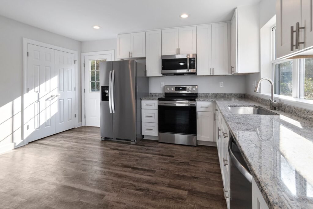 Renovated kitchen with white cabinets, stainless steel appliances and wood-look flooring